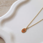 détail collier doré femme pendentif médaille étoile émail orange acier inoxydable