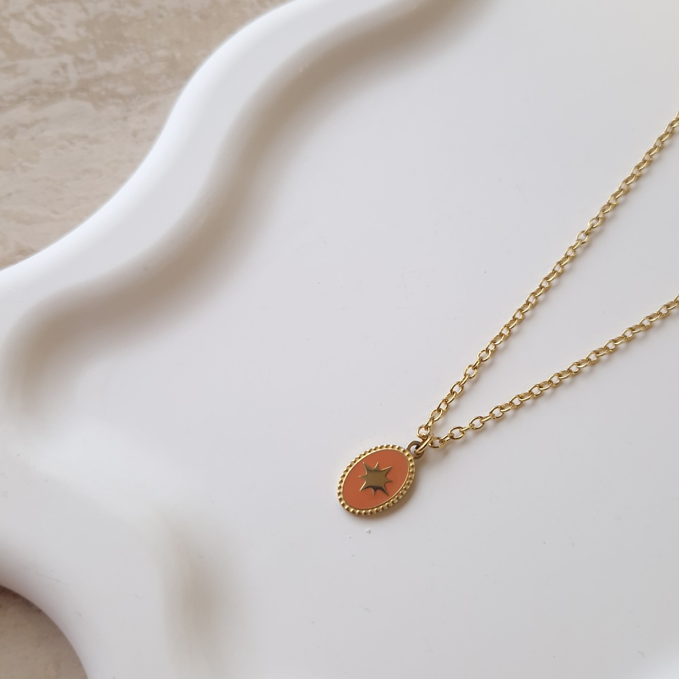 détail collier doré femme pendentif médaille étoile émail orange acier inoxydable